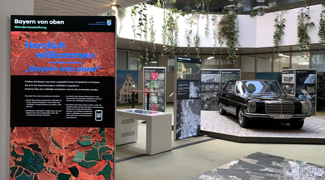 Wanderausstellung Blick in den Ausstellungsraum, das Krumbacher Rathaus-Foyer. Links eine Ausstellungstafel, rechts eine schwarze Limousine, die dauerhaft im Rathaus-Foyer steht.